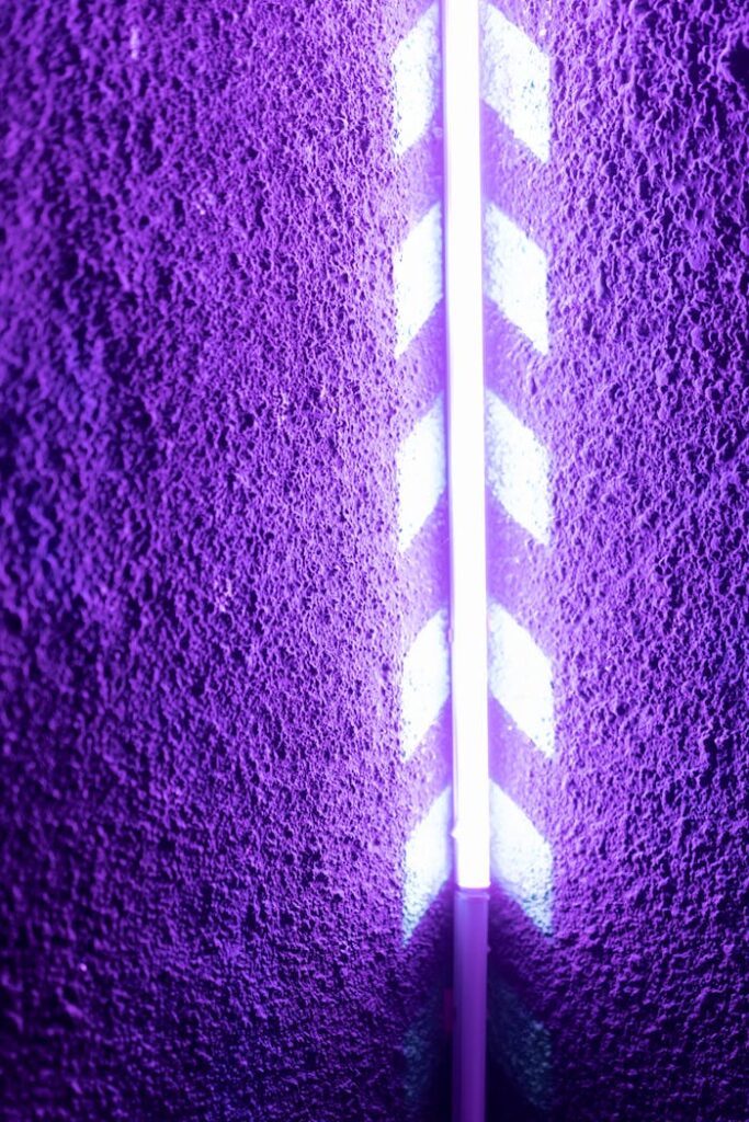 Purple textured wall illuminated by a bright neon light creating a futuristic glow.